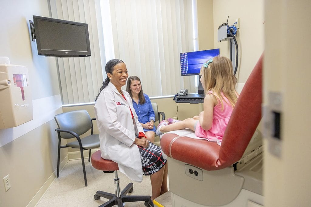 A doctor explaining results to a young girl and her mom, representing the importance of Kosair childrens and addiction recovery funding.