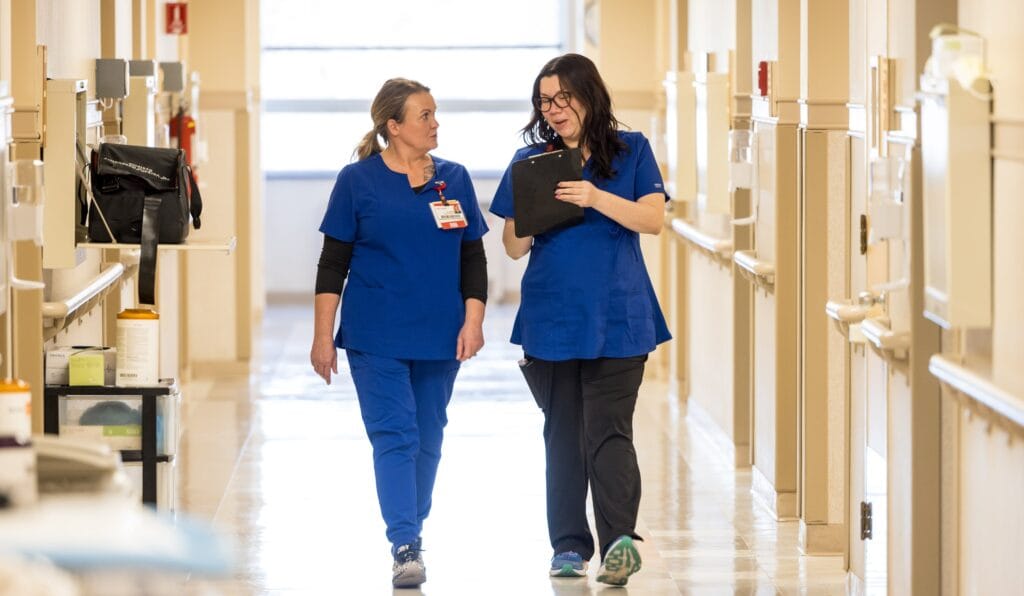 Two nurses walking through a hallway in a hospital, speaking about Curing blindness research.